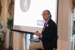 This is a photograph of Bruce Weindruch speaking to the audience at a PRSA event.